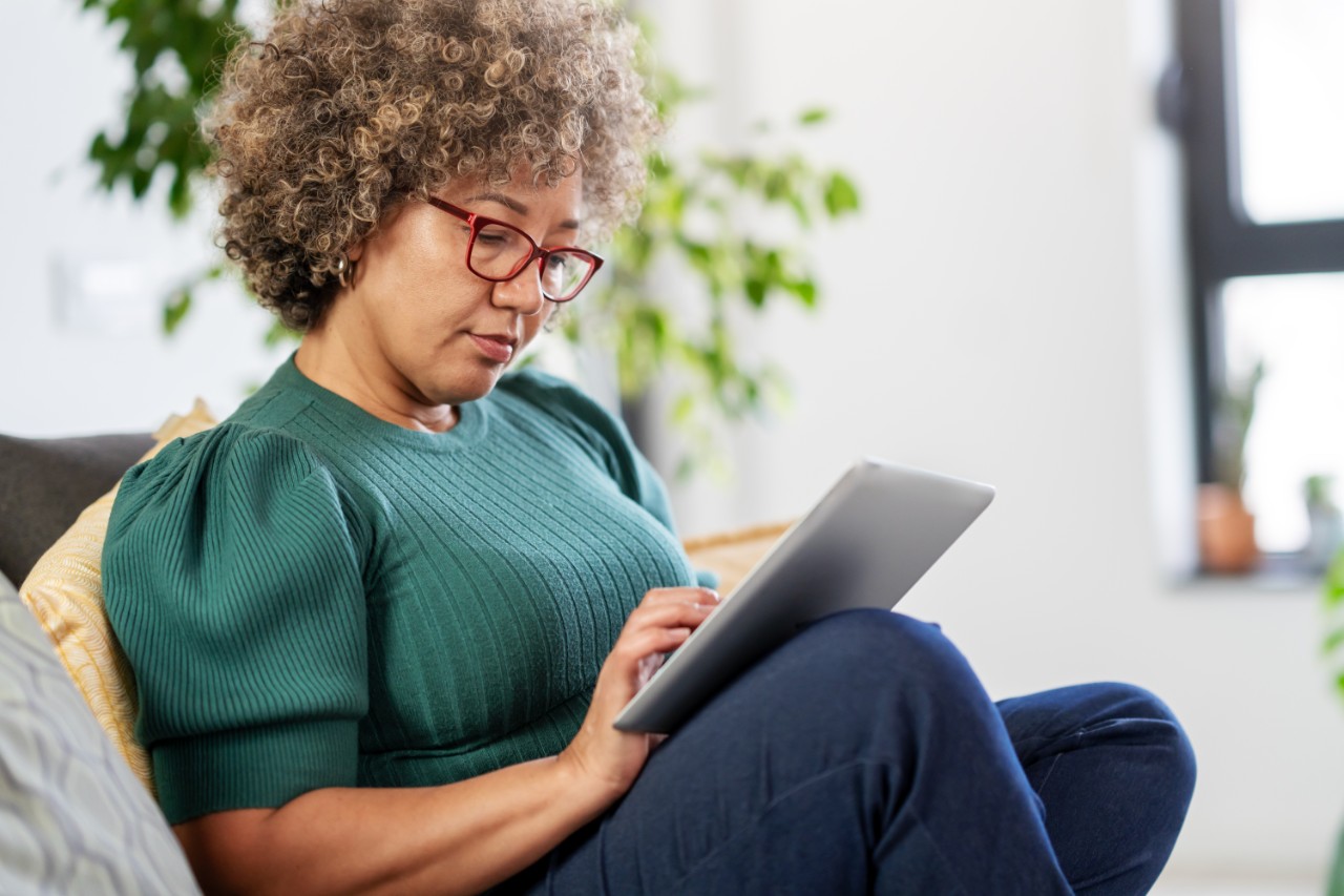 Vrouw op bank met ipad of tablet