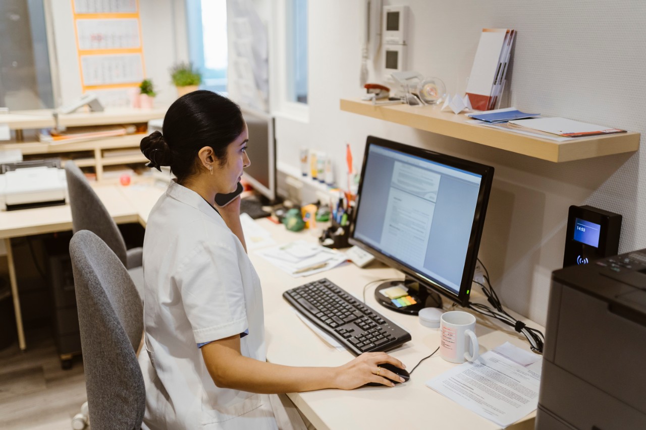 Arts of assistente aan telefoon achter bureau met computer