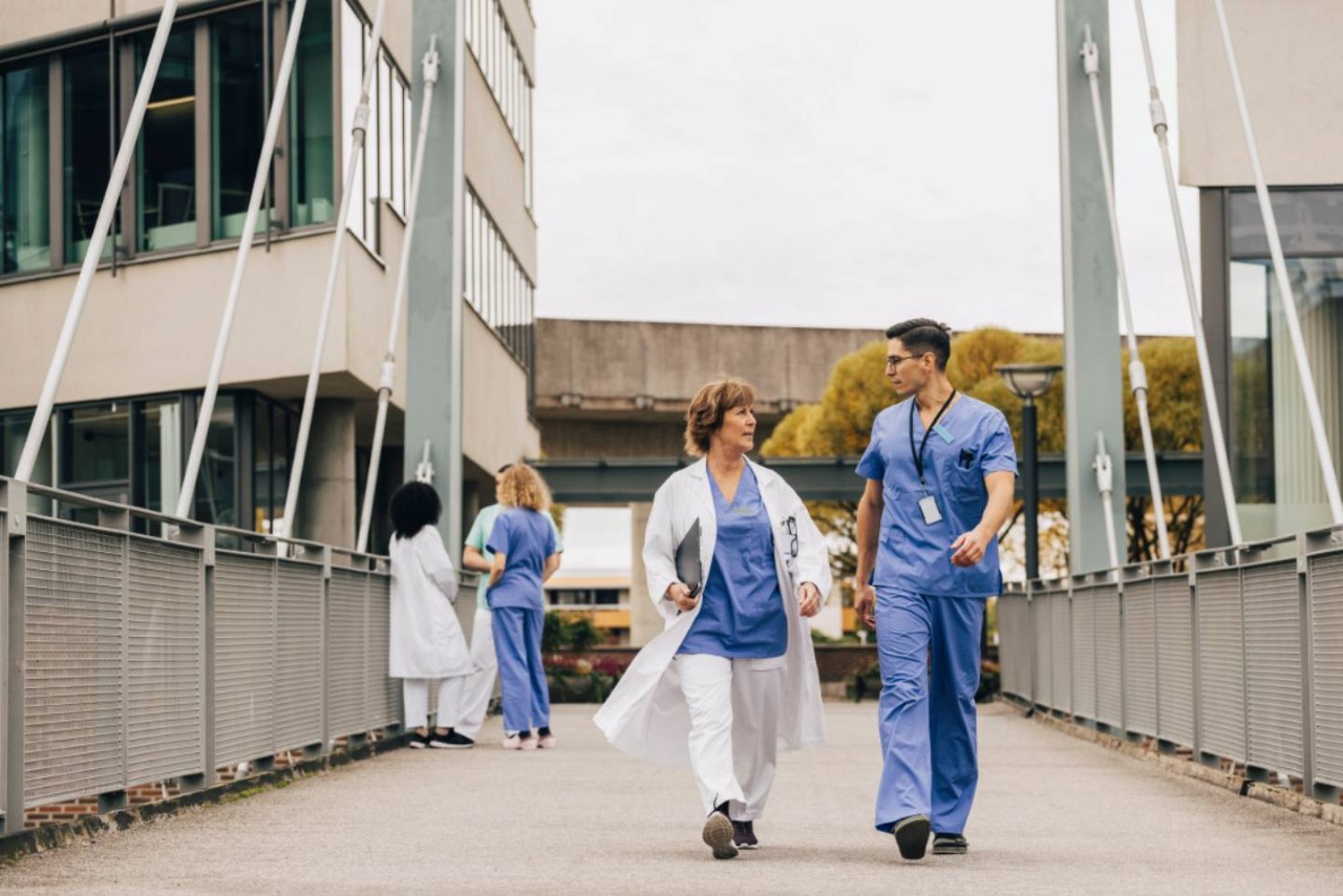 Verpleegkundigen en artsen lopen buiten over een brug