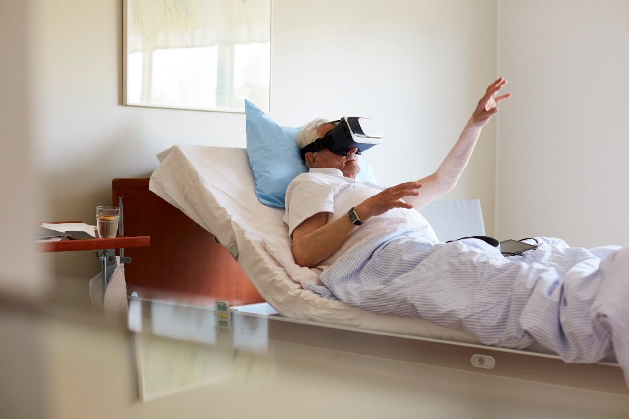 Oudere man in bed met VR bril op