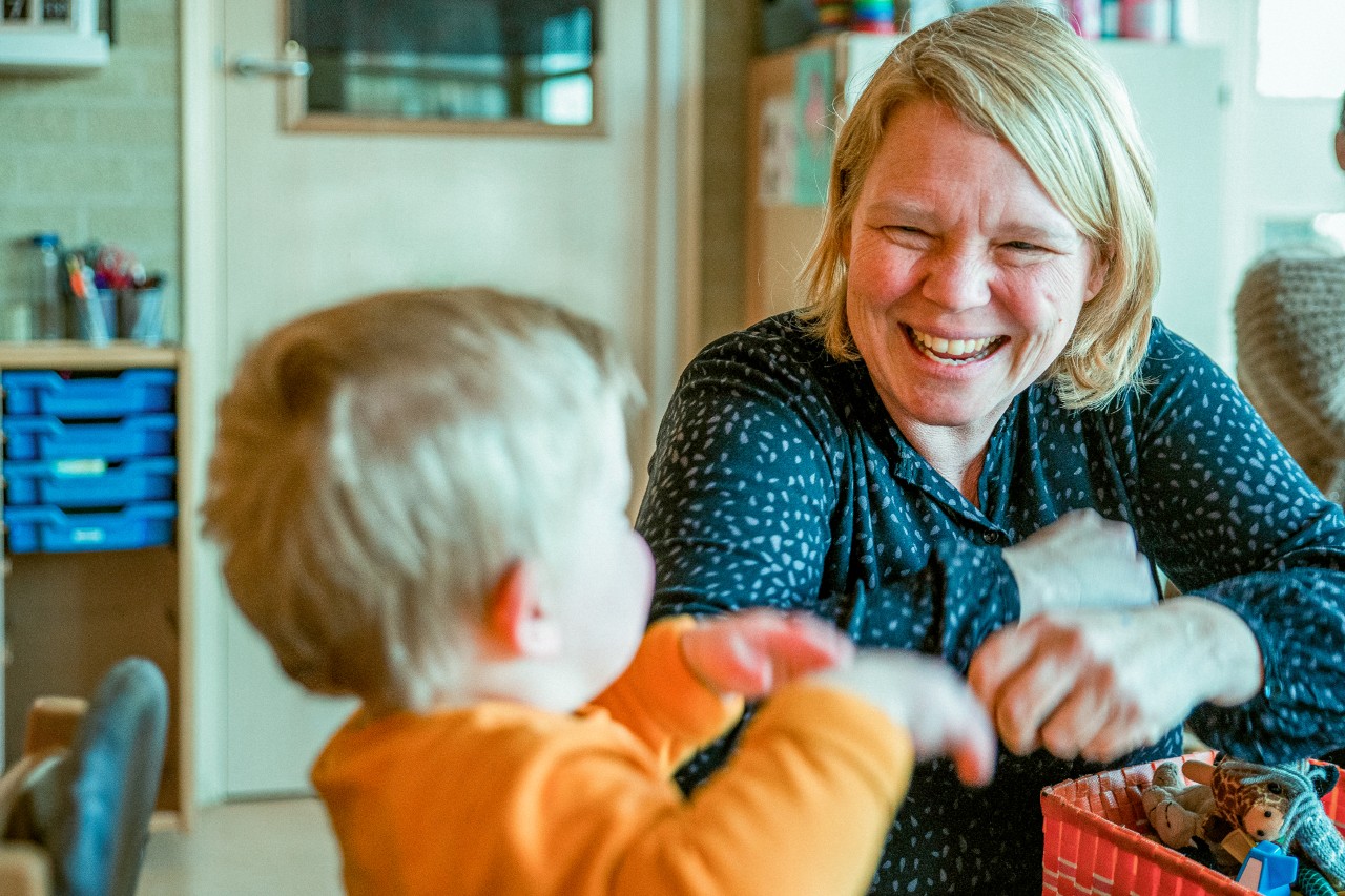 Lachende kinderjuf met peuter