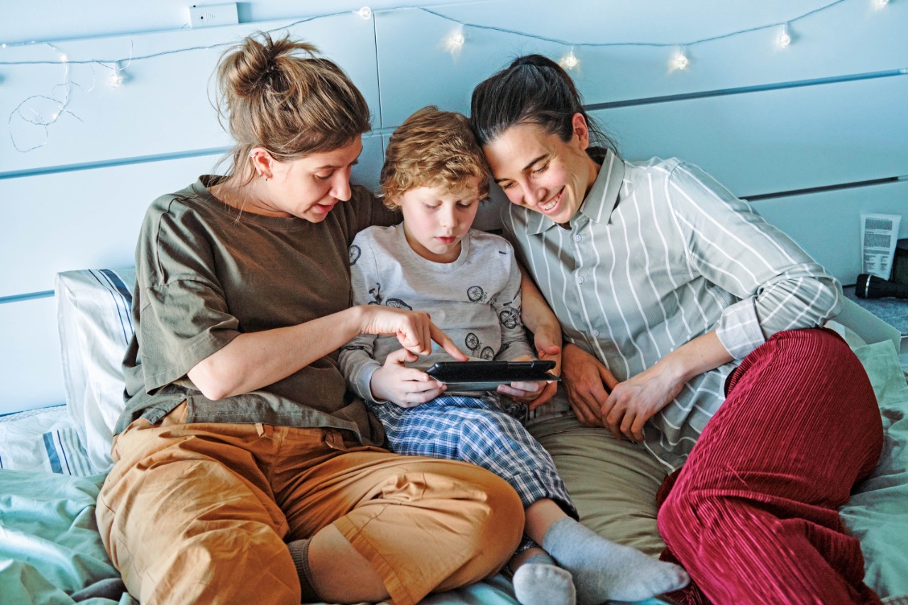 twee vrolijke vrouwen met kind in bed