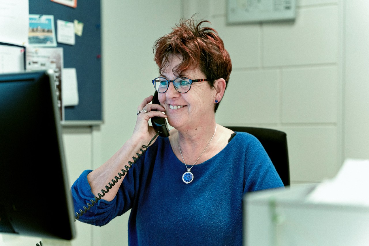 Vrouw in blauw aan de telefoon achter computer