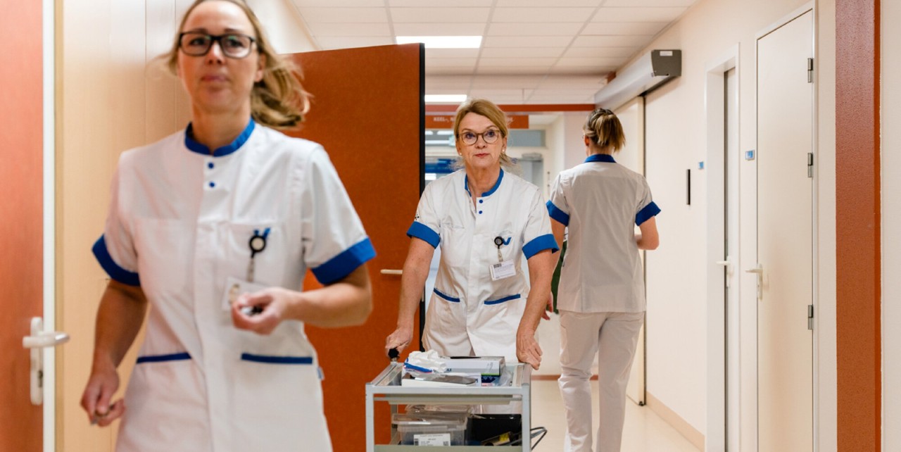 Drie verpleegsters lopen door de gang van het ziekenhuis