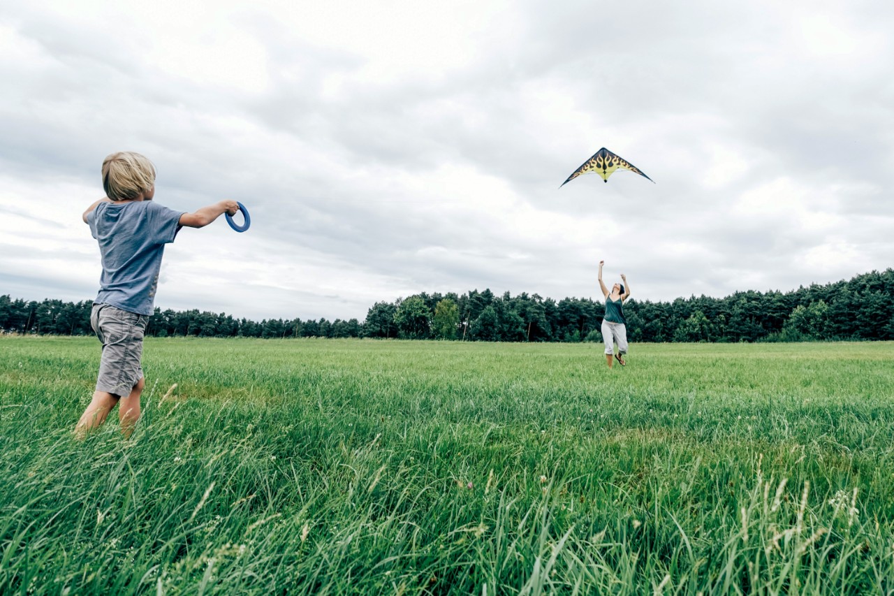 Kind en moeder spelen met vlieger in het gras