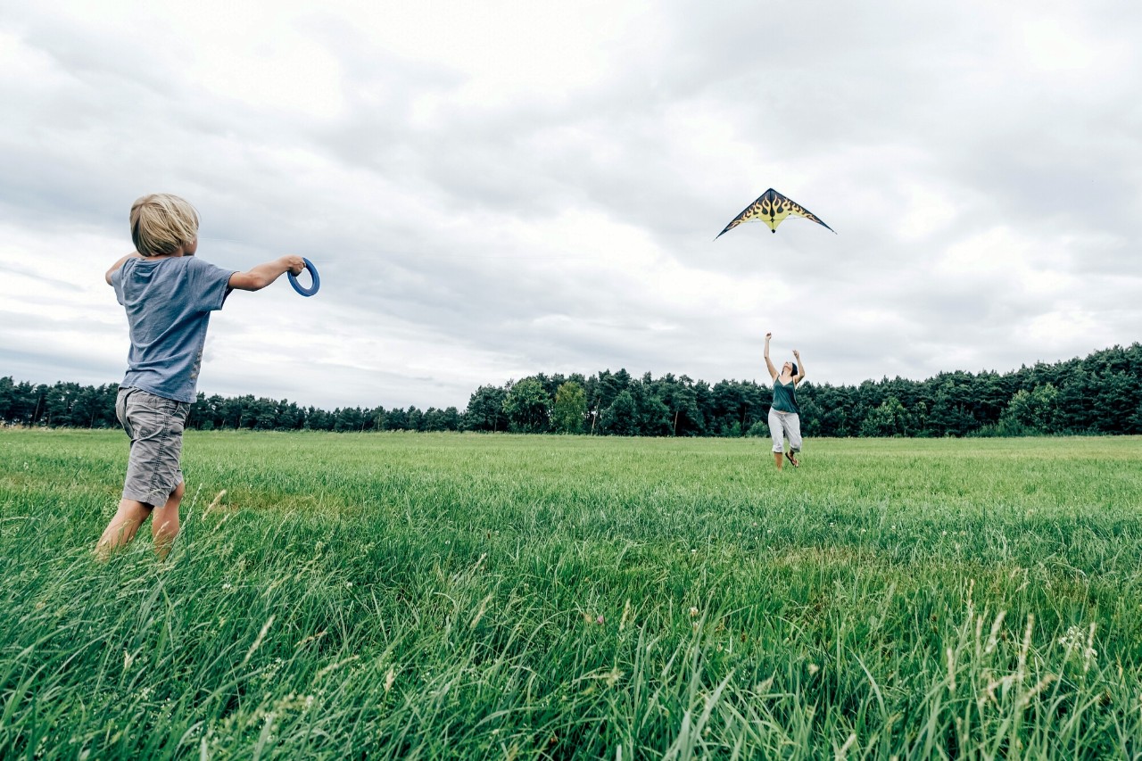 kind en moeder spelen met vlieger in het gras