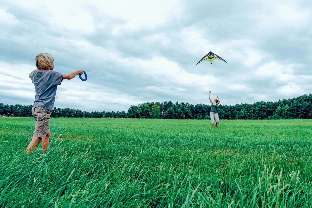 moeder en kind spelen buiten vliegeren